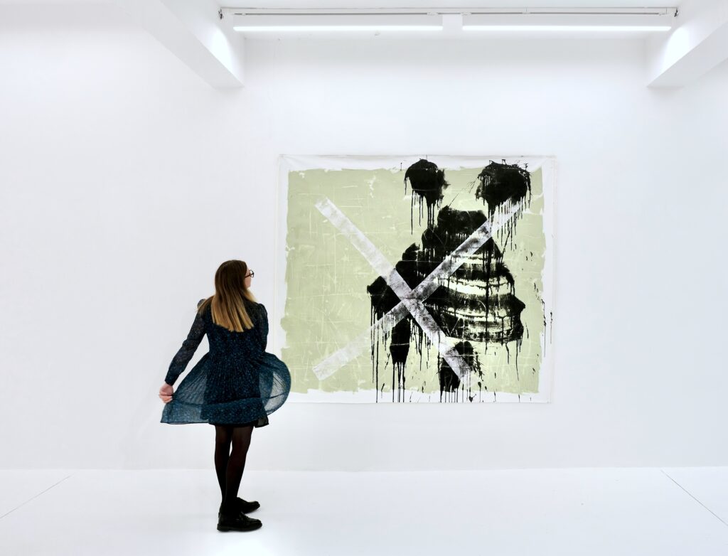 A girl watching a painting by Esmael Bahrani on a white wall in Macadam gallery
